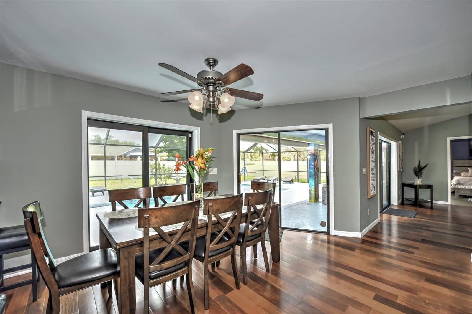 A spacious dining area with a wooden table and chairs, a ceiling fan, and large sliding glass doors leading to an outdoor patio.