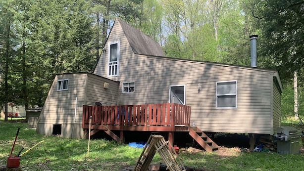 Une maison à deux étages avec une terrasse en bois et une cheminée.