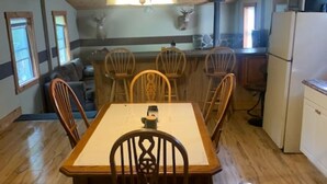 Une cuisine aux murs lambrés, avec une table et des chaises, un réfrigérateur et un four à micro-ondes.