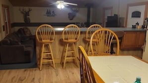 Un espace repas comprenant une table et des chaises en bois, un ventilateur de plafond et des lampes fixées au mur.