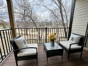 Relax on the covered porch with two comfortable chairs and a small table, perfect for enjoying a quiet moment.