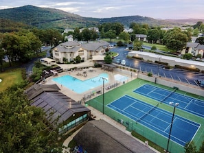 Relax by the pool or play a game of tennis in a serene natural setting surrounded by lush greenery and traditional architecture.