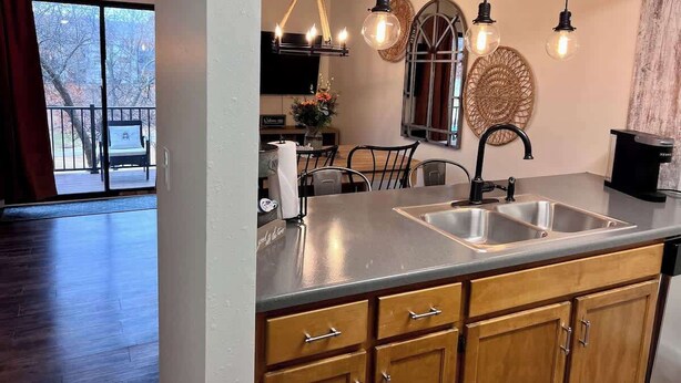 Une cuisine dotée d’un grand îlot central, d’appareils électroménagers en acier inoxydable et de luminaires suspendus.