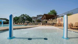 Une piscine avec des chaises longues et un espace salon abrité.