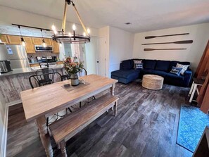 Una cocina moderna con una mesa de comedor de madera, una lámpara de araña y un sofá azul en una sala de estar.