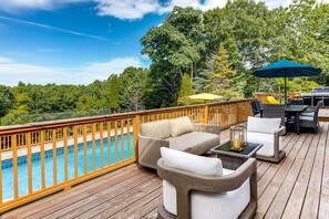 Eine Terrasse mit Pool, Gartenmöbeln und Grillplatz.