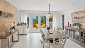 A spacious dining area with a wooden table and chairs, a chandelier, and a view of the outdoor patio.
