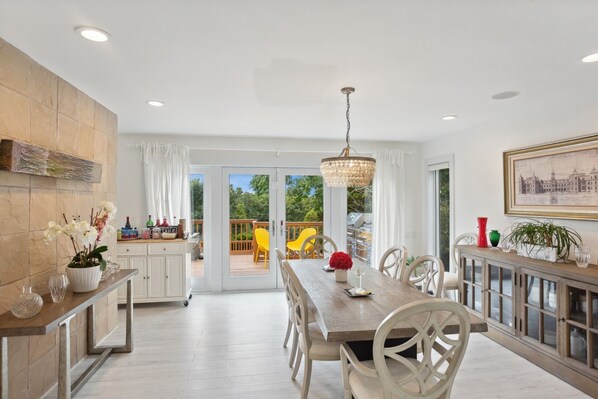Un comedor amplio con una mesa y sillas de madera, un candelabro y vistas del patio exterior.