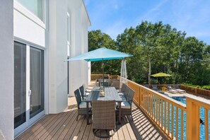 Una terraza con piscina, mobiliario exterior y vista a árboles.