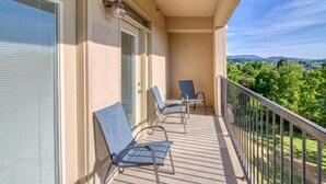 A balcony with three chairs, a door, and a view of a cityscape. - 8 min to Dollywood- Close to parkway River and Mountain Views 2BR/2BA Sleeps 6  (Sevierville)