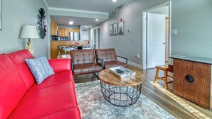 A modern living room with a red sofa, two brown leather chairs, a coffee table, and a kitchen in the background. - 8 min to Dollywood- Close to parkway River and Mountain Views 2BR/2BA Sleeps 6  (Sevierville)