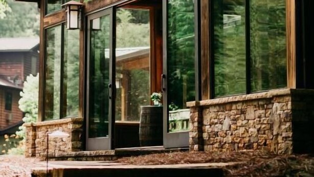 A modern house with large glass windows, stone foundation, and a wooden roof. - Sylvan Valley Lodge & Cellars (Sautee Nacoochee)