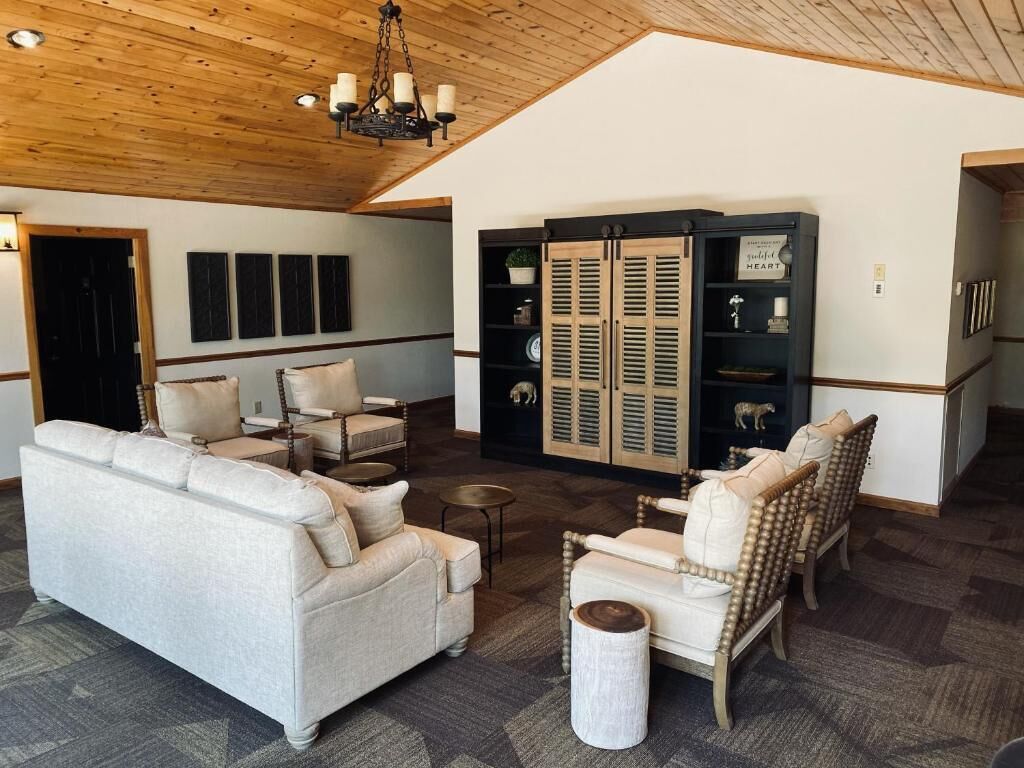 A spacious living room with a high ceiling, a fireplace, and a built-in bookshelf.