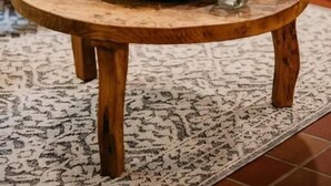 A round wooden table with a sign reading "WINE TASTING DAILY," a stack of folded towels, and two glass mugs on a patterned rug. - Sylvan Valley Lodge & Cellars (Sautee Nacoochee)