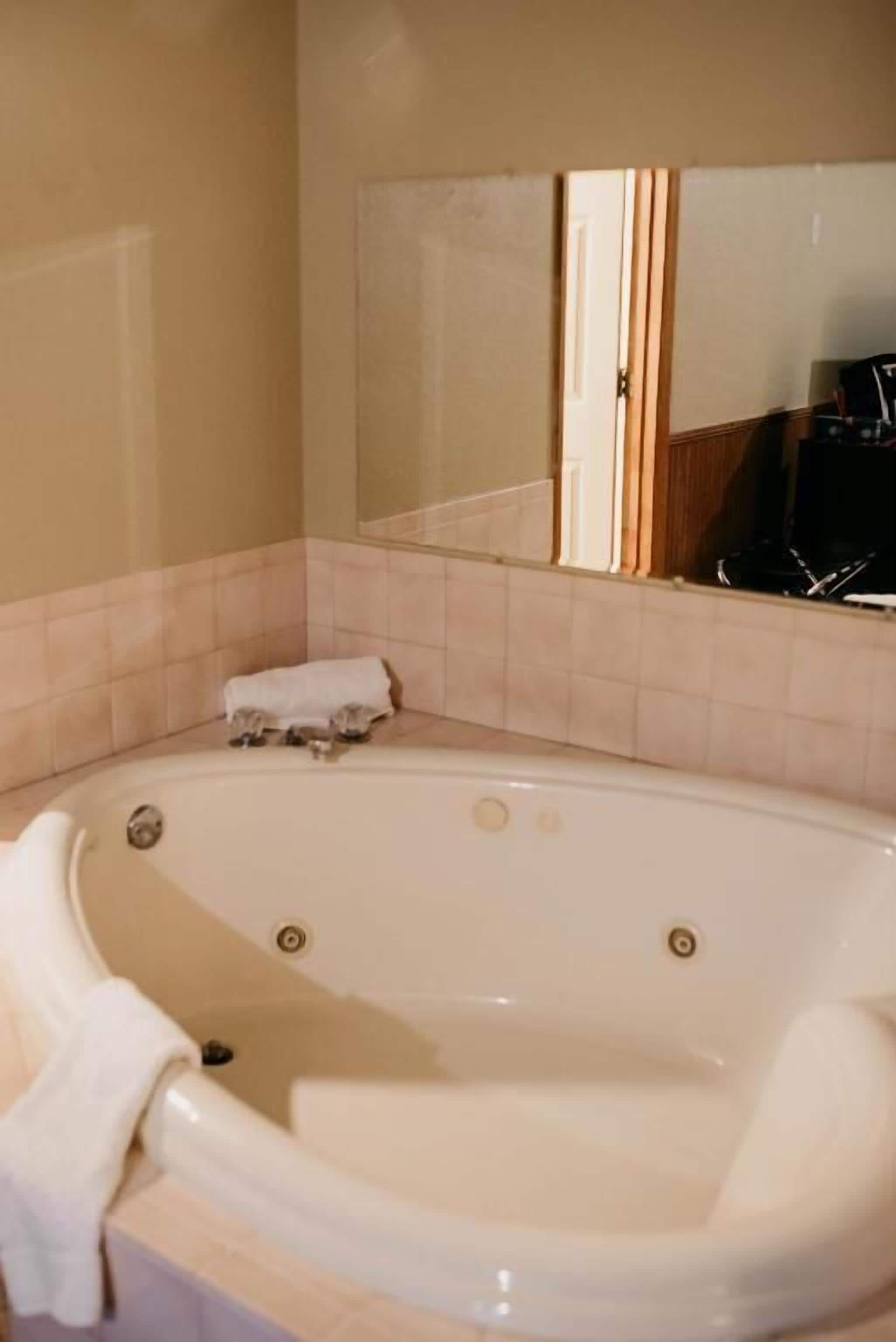 A bathroom with a bathtub, a mirror, and a towel.
