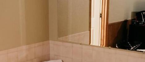 A bathroom with a bathtub, a mirror, and a towel.