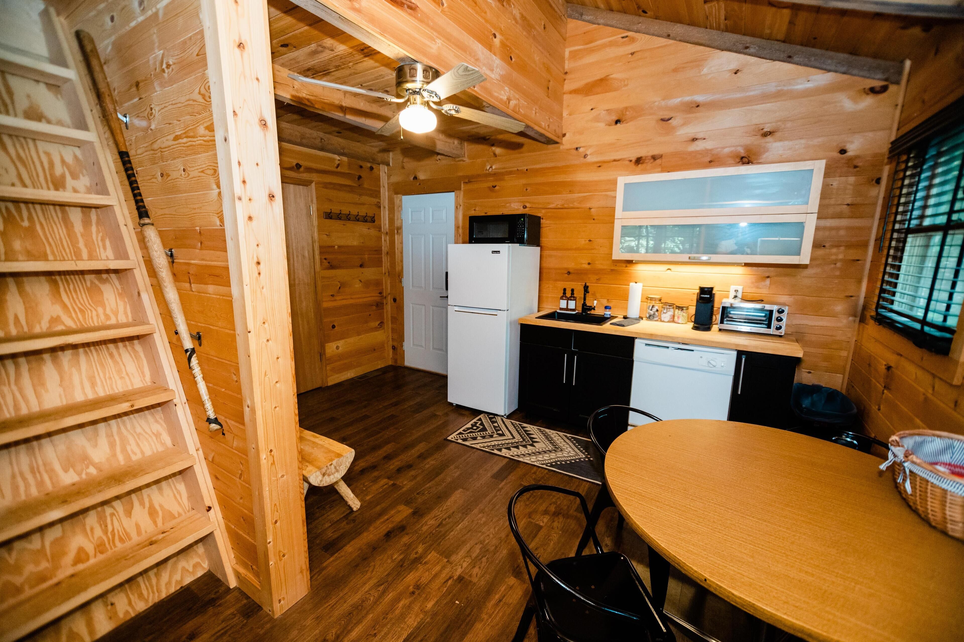 Un interior de madera con una zona de cocina que incluye un refrigerador, microondas y una mesa de comedor con sillas.
