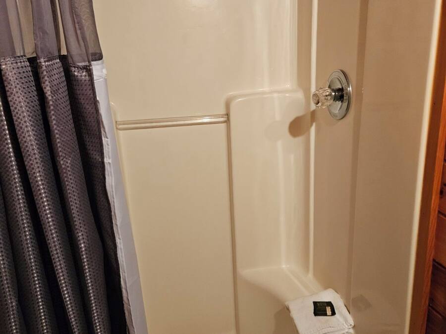 Een douchegedeelte met een houten plafond, een douchekop en een klein handdoekrek.