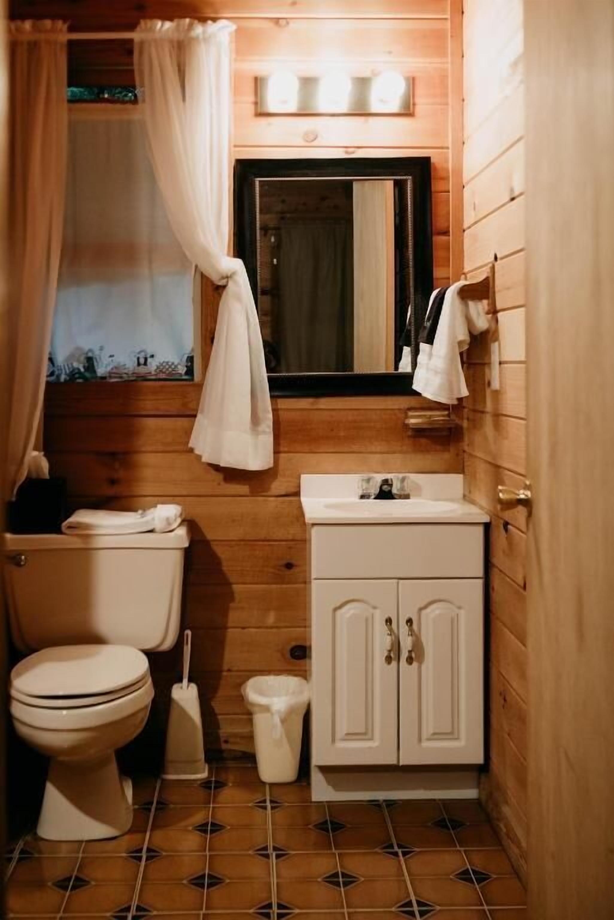 Un baño de madera pequeño y funcional con inodoro, lavamanos y armario.