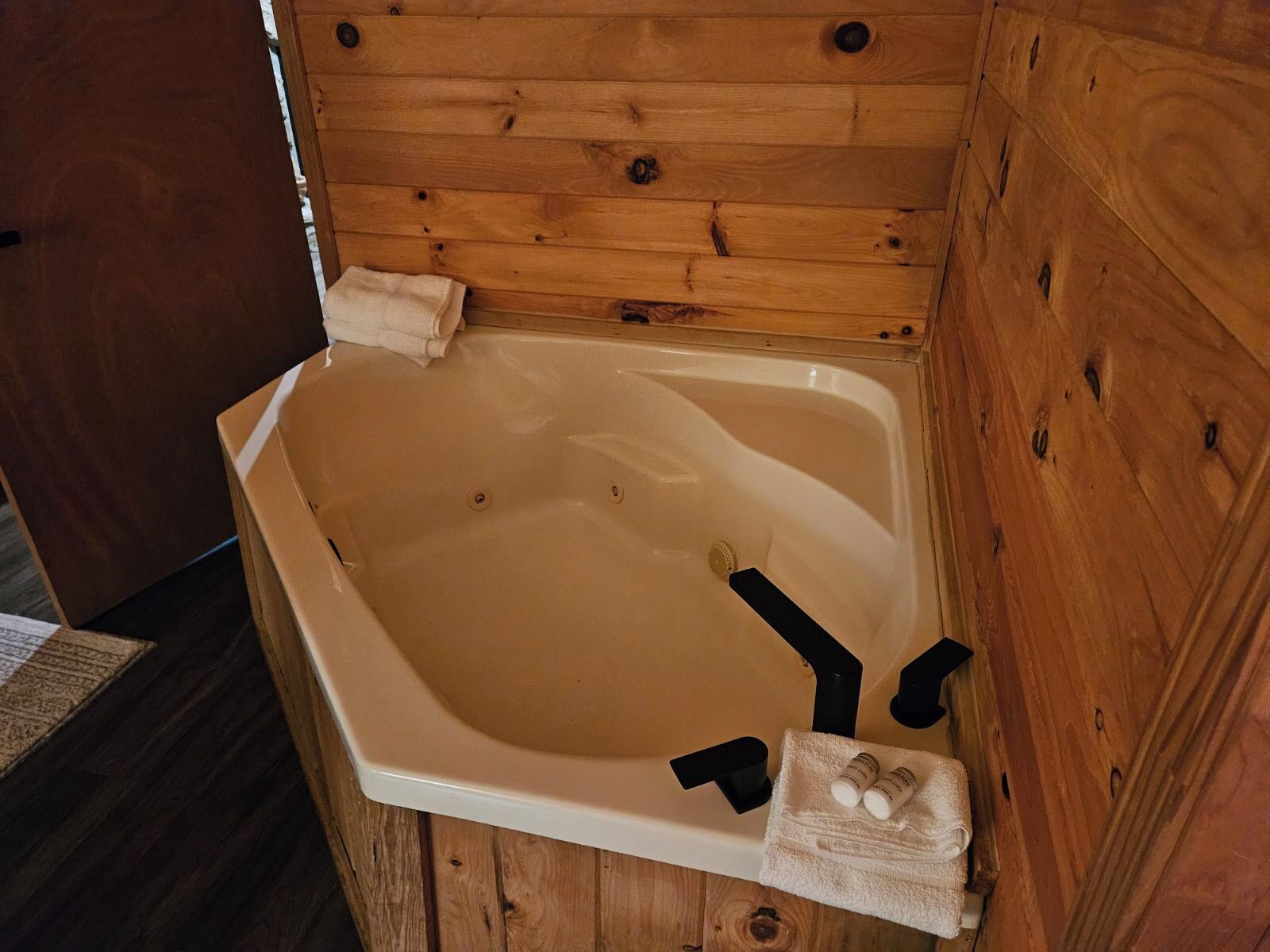 Une cabane en bois avec une baignoire blanche, des serviettes et des articles de toilette.