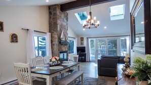 A dining area with a stone pillar, a chandelier, and a view of the outdoors through large windows. - Sun Drenched Lakefront Cove (Thompson)