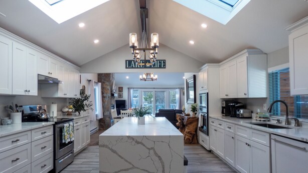 A modern kitchen with white cabinetry, a marble island, and a skylight above. - Sun Drenched Lakefront Cove (Thompson)