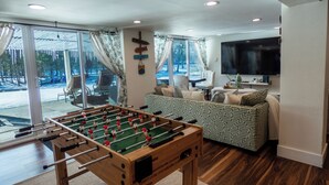 A cozy living room with a foosball table, a sofa, and a TV. - Sun Drenched Lakefront Cove (Thompson)