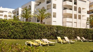 A modern building with multiple balconies and a well-maintained lawn with sun loungers. - Lovely apartment for 4 guests with pool, A/C, WIFI, TV and terrace (Armação De Pêra)