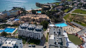 An aerial view of a coastal resort with multiple buildings, a beach, and a cliff. - Lovely apartment for 4 guests with pool, A/C, WIFI, TV and terrace (Armação De Pêra)