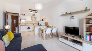 A modern apartment with a living room, dining area, kitchen, and a TV. - Lovely apartment for 4 guests with pool, A/C, WIFI, TV and terrace (Armação De Pêra)