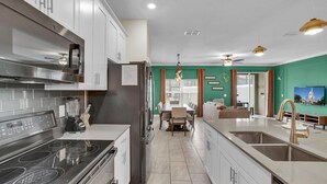 Una cocina moderna con estufa integrada, un refrigerador y un comedor con mesa y sillas.
