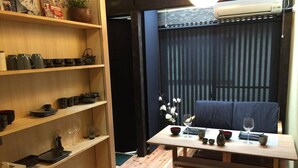 A compact room with a wooden dining table set for two, a bench, and shelves with kitchenware.