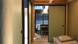 A traditional Japanese-style room with tatami flooring, a sliding door, and a low wooden ceiling.