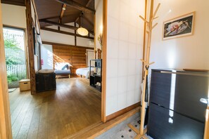 A room with a bed, a wooden floor, a black refrigerator, and a wooden cabinet.
