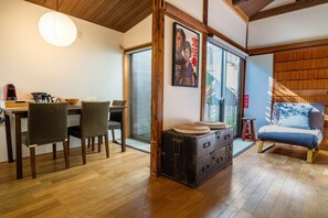 A traditional Japanese-style room with a wooden floor, a dining table with chairs, a sofa, a cabinet, and a large window. - Ikebukuro Nigo - Tokyo architectural small villa (Tokyo)