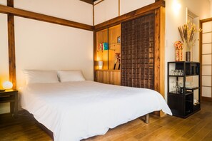 A bedroom with a large bed, wooden beams, a bookshelf, and a nightstand. - Ikebukuro Nigo - Tokyo architectural small villa (Tokyo)