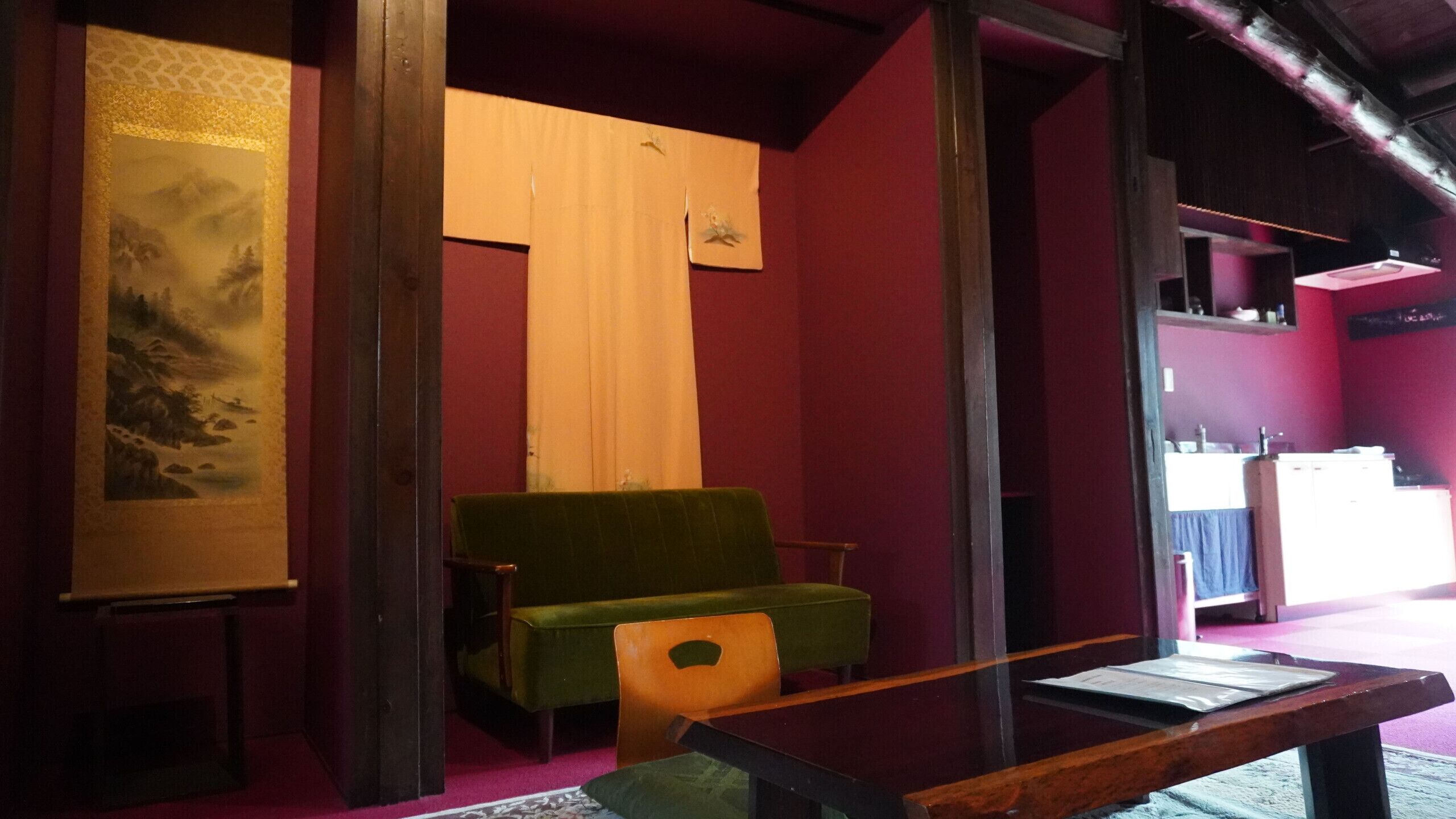 Una habitación con un sofá verde, una mesa de madera y un cuadro grande en la pared.