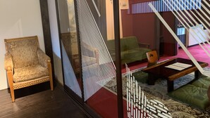 Een kamer met een klassieke fauteuil, een groene bank en een kamerkleed met patroon.