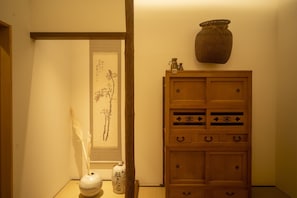 Um quarto tradicional japonês com um painel shoji, um armário de madeira com gavetas e uma cesta suspensa trançada.