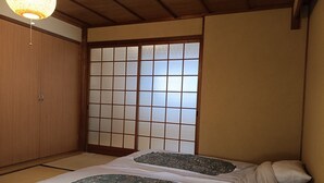 Une pièce traditionnelle japonaise avec un sol recouvert de tatamis, une porte coulissante en papier de riz (shoji) et un futon agrémenté de motifs floraux.
