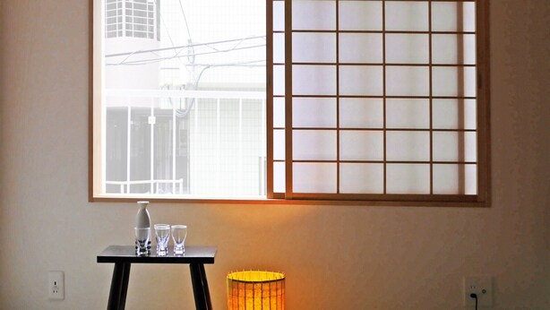 A room with tatami flooring, a low table with glasses, a candle, and cushions.