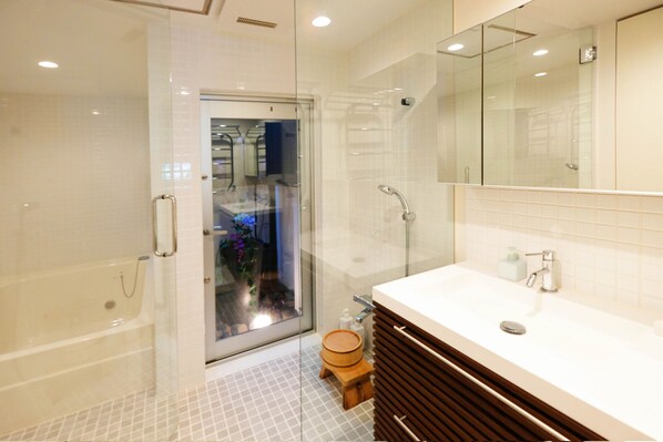 A modern bathroom with a glass shower enclosure, a wooden toilet, and a large mirror above the sink.