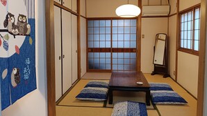 A traditional Japanese room with tatami flooring, a shoji screen door, and a wooden table with cushions. - Gion Rokudo - Comfortable house in Gion (Kyoto)