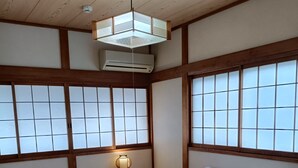 A traditional Japanese room with tatami flooring, a futon bed, a shoji screen, a hanging light fixture, and a small wooden table. - Gion Rokudo - Comfortable house in Gion (Kyoto)