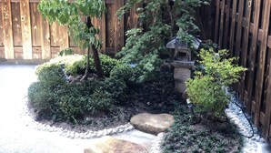 A garden with a wooden fence, a stone birdhouse, and various shrubs and trees. - Sakura Aburaya - Perfect traditional & comfortable house (Takayama)