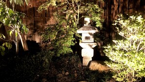 A stone lantern in a garden with a wooden fence in the background. - Sakura Aburaya - Perfect traditional & comfortable house (Takayama)