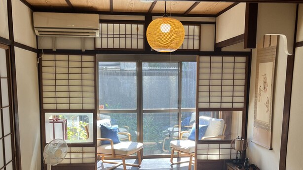Een traditionele Japanse kamer met tatami vloerbedekking, een lage tafel, twee stoelen, een waaier en een hangende lamp.