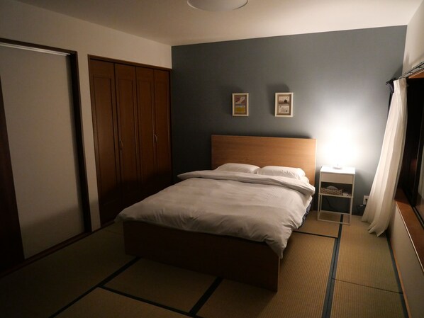 Un dormitorio con cama, mesita de noche, armario y una pared con dos cuadros.