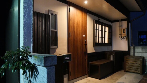A modern building with a wooden door, a small window, and a bench outside.