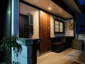 Un edificio moderno con puerta de madera, una ventana pequeña y un banco en el exterior.